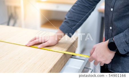 Male hand using tape measure on countertop Male hand using tape measure on countertop 54901166