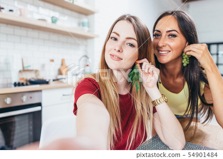 Women having breakfast in kitchen playing with food and taking selfie. 54901484