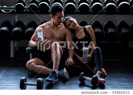 Happy couple relax after exercise in gym Happy couple relax after exercise in gym 54902631