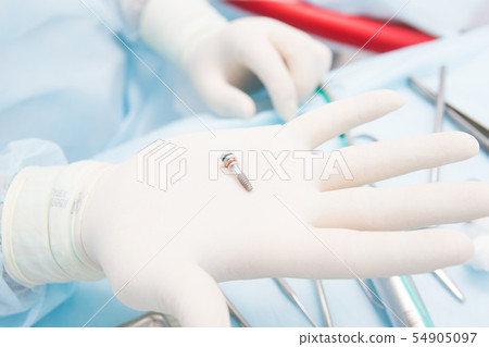 Dentist doctor holds dental implant  54905097