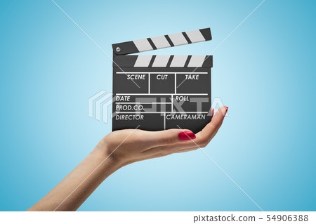 Side closeup of woman's hand facing up and holding clapperboard on light-blue gradient background. Side closeup of woman's hand facing up and holding clapperboard on light-blue gradient background. 54906388