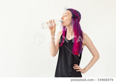 Young girl hipster with colored hair drinks water from a bottle after intense physical training in Young girl hipster with colored hair drinks water from a bottle after intense physical training in 54906979