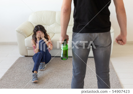 domestic violence, alcoholic and abuse concept - drunk man with bottle abusing his wife lying on the domestic violence, alcoholic and abuse concept - drunk man with bottle abusing his wife lying on the 54907423