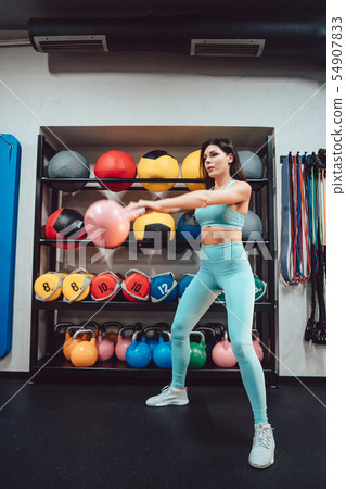 Young adult girl doing strength exercises in the gym 54907833