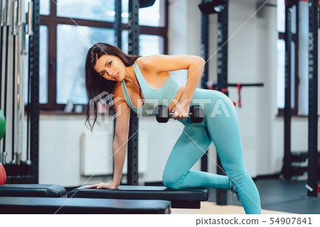 Young adult girl doing strength exercises in the gym Young adult girl doing strength exercises in the gym 54907841