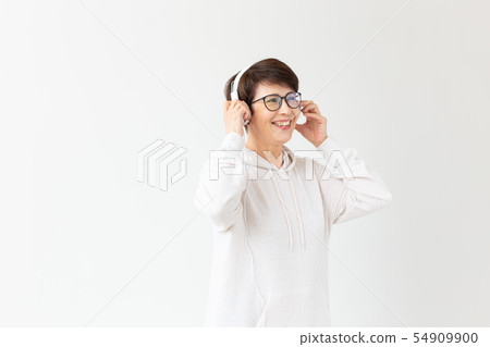 Beautiful woman 40-50 years old listening music in big headphone on white background with copy space Beautiful woman 40-50 years old listening music in big headphone on white background with copy space 54909900