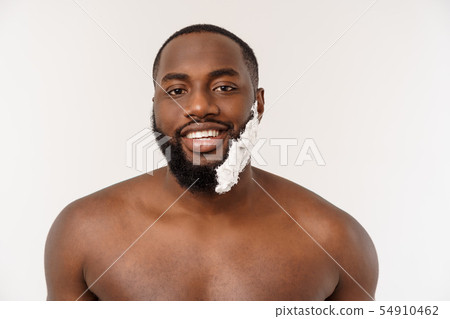 African American man smears shaving cream on face by shaving brush. Male hygiene. Isolated on white 54910462