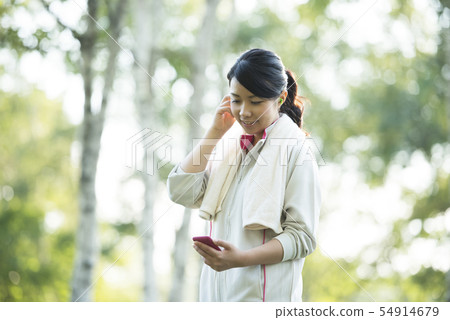 Sporty woman listening to music in nature Sporty woman listening to music in nature 54914679