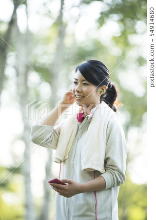Sporty woman listening to music in nature Sporty woman listening to music in nature 54914680
