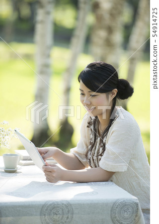 Woman operating a tablet in nature 54914725