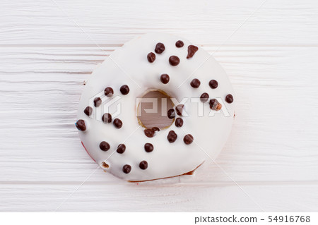 White donut with chocolate crunchies. 54916768