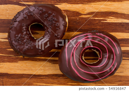Two chocolate donuts on wooden background. 54916847