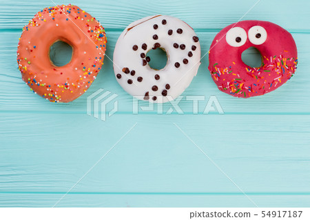 Three different donuts on blue wooden background. Three different donuts on blue wooden background. 54917187