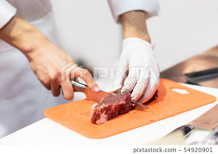 Chef cutting fresh raw meat with knife in the Chef cutting fresh raw meat with knife in the 54920901