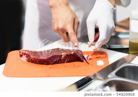 Chef cutting fresh raw meat with knife in the Chef cutting fresh raw meat with knife in the 54920908