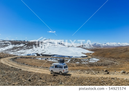 A white van with luggage running along mountain. 54925574