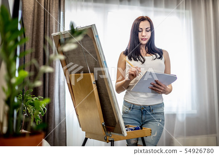 Young woman artist painting at home creative tools close-up 54926780