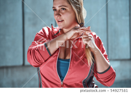 Ready to do my best. Cute plus size woman in sport clothes adjusting her long hair and looking away Ready to do my best. Cute plus size woman in sport clothes adjusting her long hair and looking away 54927581