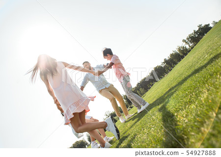 Having fun. Back view of young family holding hands and dancing in the circle while spending time Having fun. Back view of young family holding hands and dancing in the circle while spending time 54927888