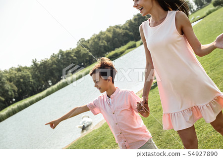 You should see it Cute little boy pointing away and smiling while walking with his mother near the 54927890