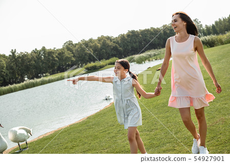 Enjoying time with mother. Cute little girl pointing away and smiling while walking with her mother 54927901