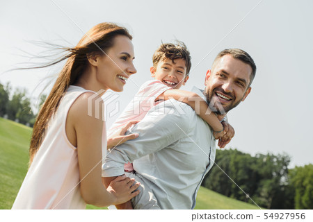 I love my parents Young and strong father carrying his happy son on shoulders while spending time 54927956