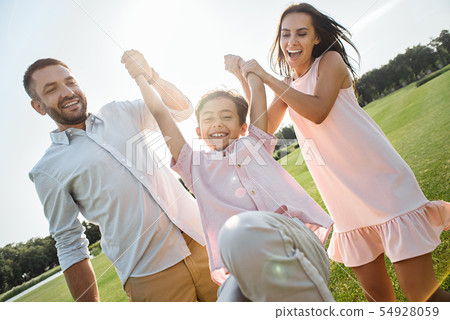 Playing with family. Full length of young and happy parents carrying their son and smiling while 54928059