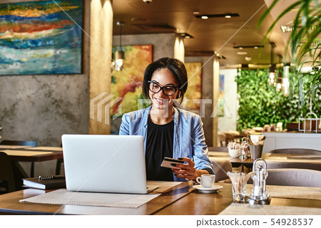 Money is only a tool. Mixed race smiling woman using credit card for shopping and paying bills on Money is only a tool. Mixed race smiling woman using credit card for shopping and paying bills on 54928537