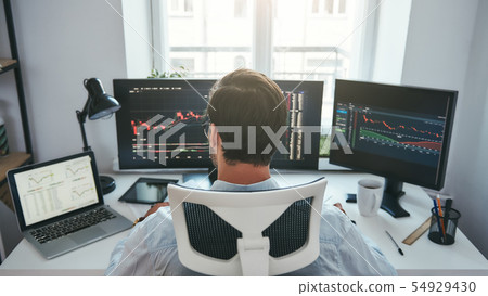Trading stocks online. Back view of young businessman or trader working with graph and charts on 54929430