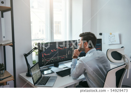Trading on world markets. Young stock market broker analyzing data and graphs on multiple computer 54929473