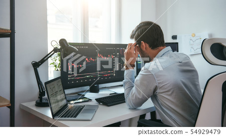 Working process. Smart male trader looking at charts on multiple computer screens and analyzing data Working process. Smart male trader looking at charts on multiple computer screens and analyzing data 54929479