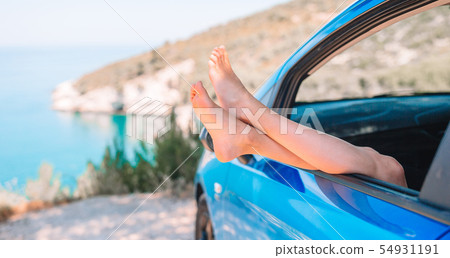 Close up of little girl feet showing from car window background sea 54931191