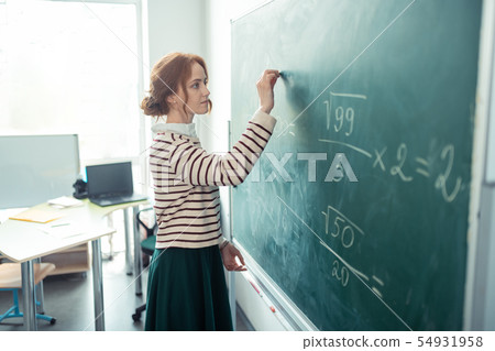 Beautiful teacher writing the task on the blackboard. 54931958
