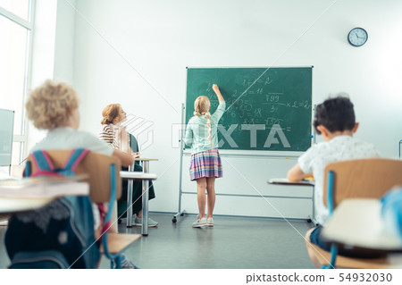School girl speaking and writing in front of the class. 54932030