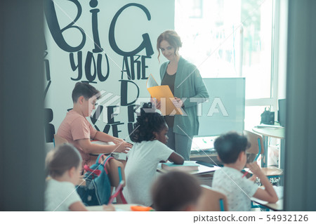 Teacher looking at her pupils with curiosity. Teacher looking at her pupils with curiosity. 54932126