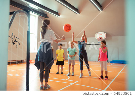 Children playing ball with their coach at sports class. Children playing ball with their coach at sports class. 54933801
