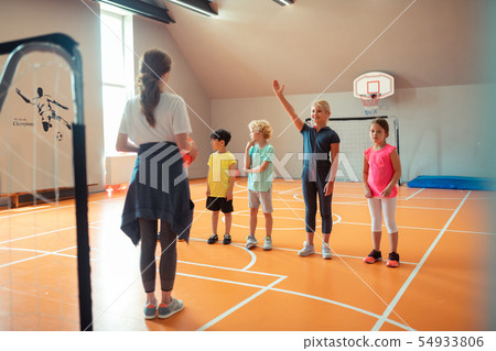 School girl raising her hand at sports lesson. School girl raising her hand at sports lesson. 54933806