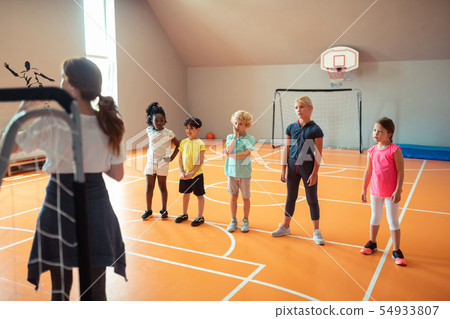 School children standing in a line during sports class. School children standing in a line during sports class. 54933807