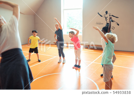 Pupils looking at their coach and trying to repeat exercises. 54933838