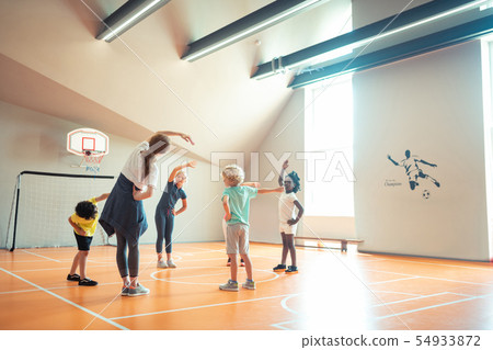 Sports teacher showing exercises to her pupils. 54933872