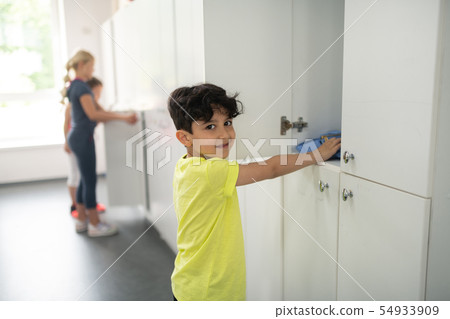 Smiling pupil standing in front of his locker. 54933909