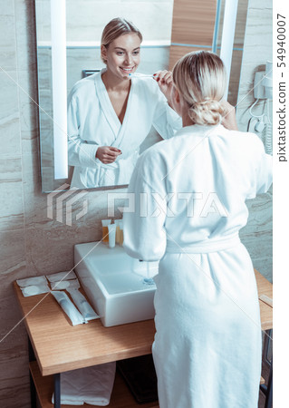 Beautiful lady with tied hair staying in front of the mirror Beautiful lady with tied hair staying in front of the mirror 54940007