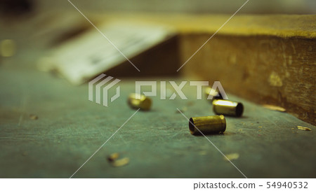 Empty pistol bullet shells on wooden table Empty pistol bullet shells on wooden table 54940532
