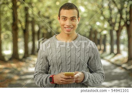 Cheerful young man spending sunny day outside Cheerful young man spending sunny day outside 54941101