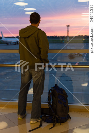 Airport passenger watching a sunset Airport passenger watching a sunset 54941553