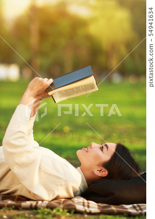 Relaxing in park. Girl reading book on grass 54941634