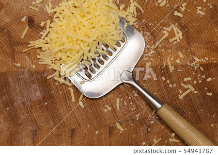 Metal cheese grater and cheese on wooden cutting board, 54941787