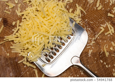 Metal cheese grater and cheese on wooden cutting board, 54941788