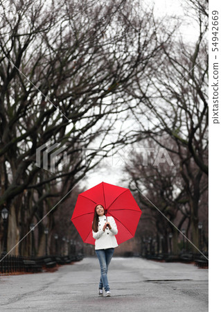 Girl with red umbrella walking in park in fall 54942669