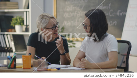 Teacher explaining to student in a classroom Teacher explaining to student in a classroom 54943236